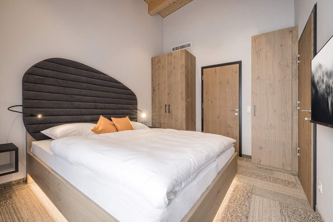 Apartment W04 — Wohn- und Schlafraum mit Schrank und Flachbild-TV